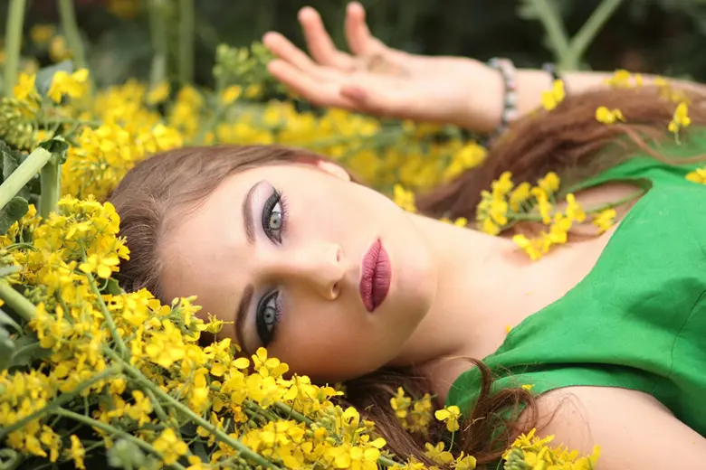 La imagen muestra a una mujer bonita acostada sobre flores