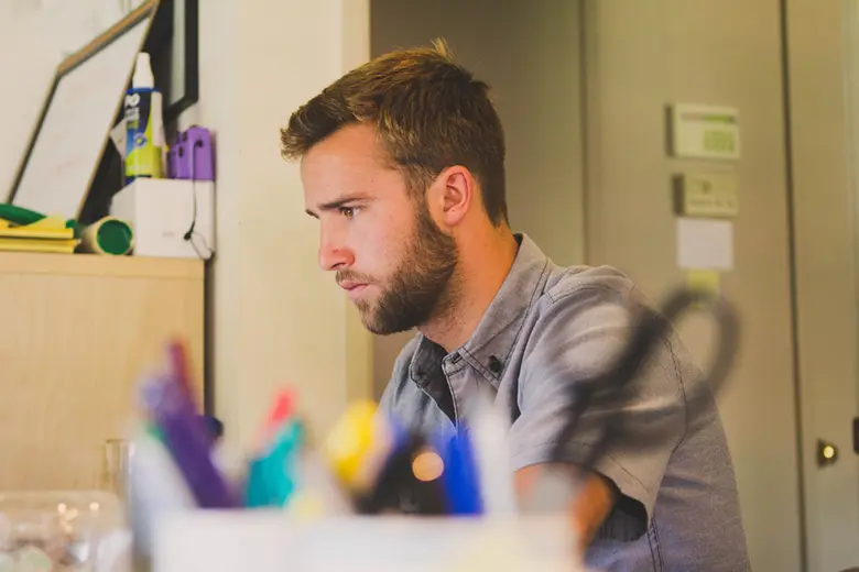 La imagen muestra a un hombre joven trabajando en su escritorio