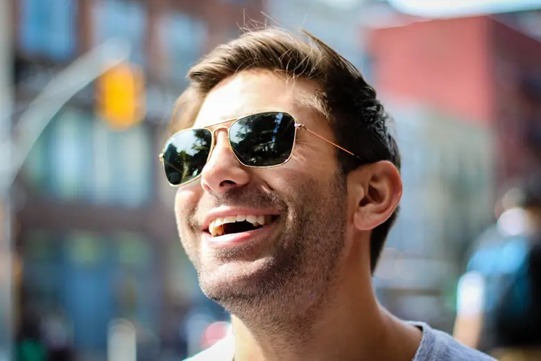 La imagen muestra a un hombre con lentes sonriente