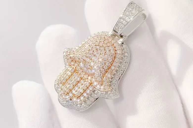 La imagen muestra una mano sosteniendo un amuleto de plata de Hamsa o mano de Fátima