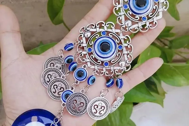 La imagen muestra una mano sosteniendo un amuleto de ojo turco o nazar